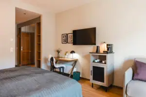 Bedroom with bed, desk and television.