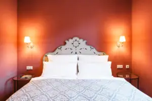 A bed with pillows and a wall lamp.