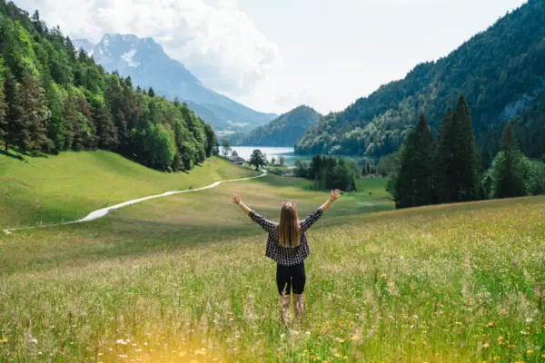 A woman is standing in a field with her arms raised.