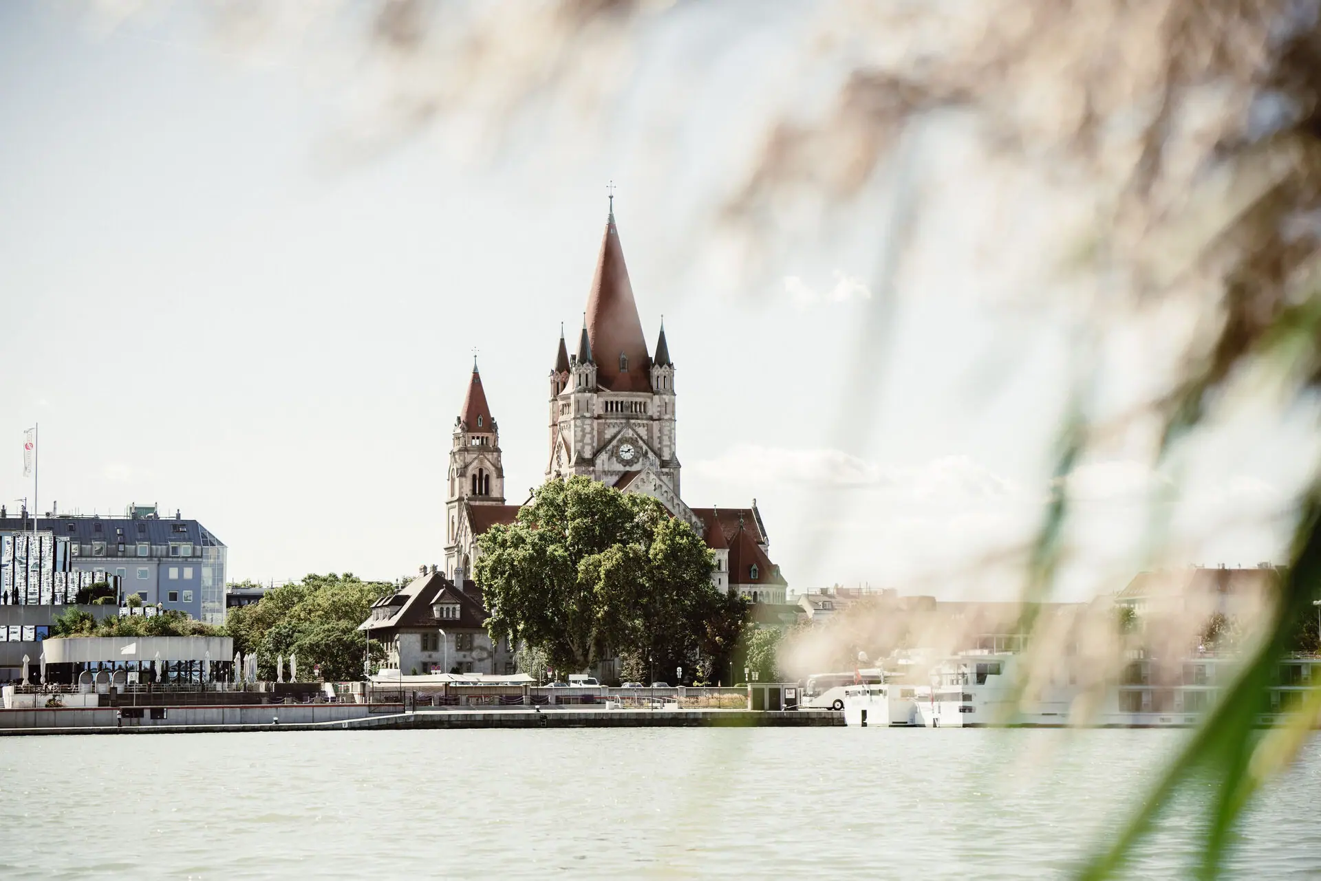 A building with a clock tower and trees by a lake.