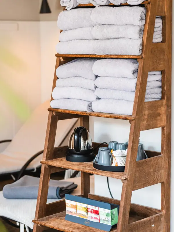 A pile of towels on a wooden shelf.
