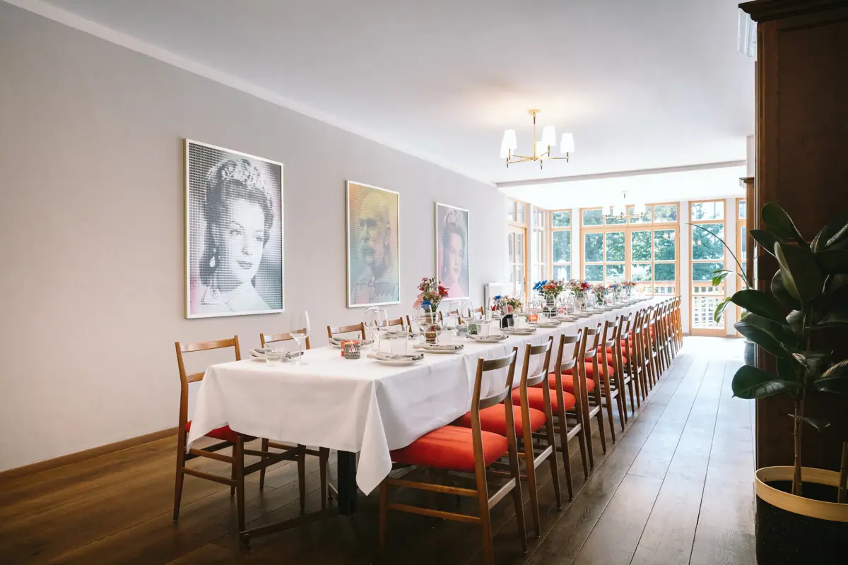 A long table with a white tablecloth and red chairs.