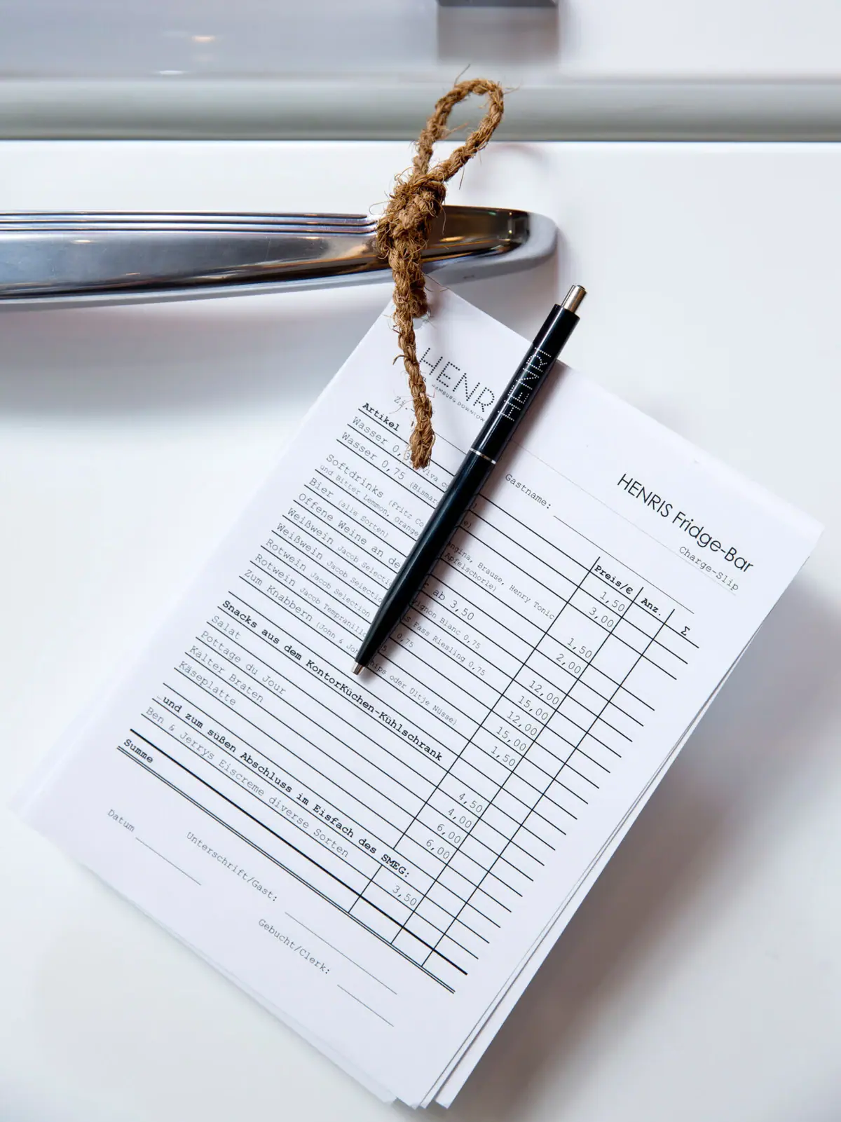 A pen on a piece of paper hangs on a fridge door.