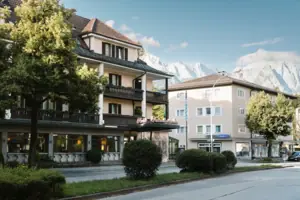 Exterior view of the HENRI Hotel in Garmisch-Partenkirchen, with trees and a road.