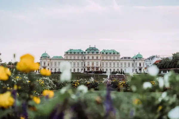 A large white building with green roofs and a garden.