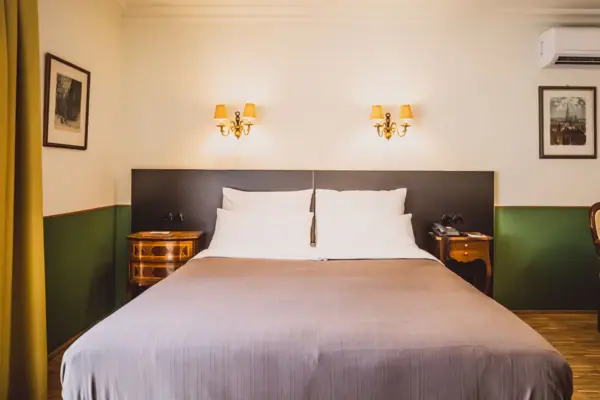A bed with two wall-mounted lamps in a hotel room.
