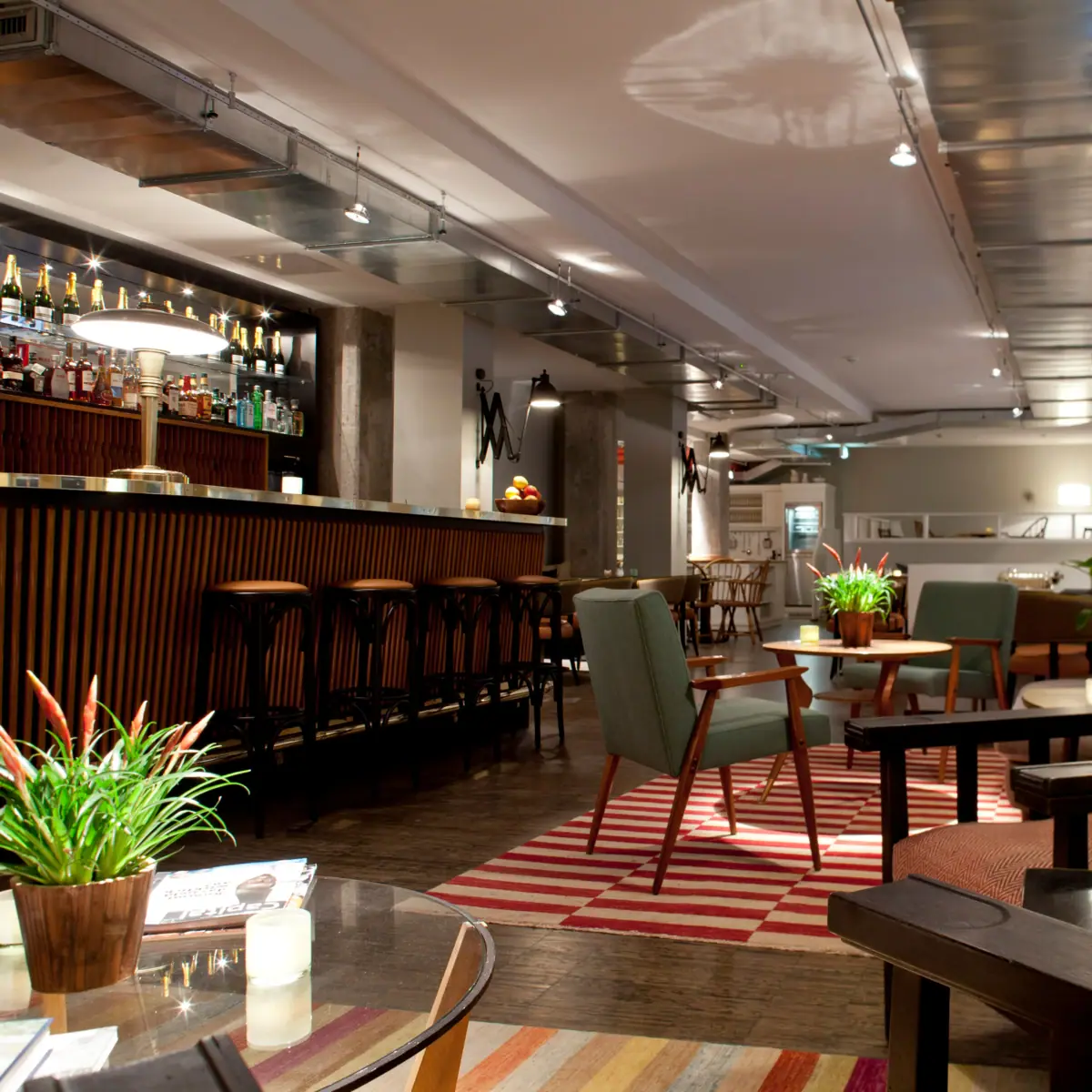 Bar counter and lounge area with armchairs at HENRI Hamburg