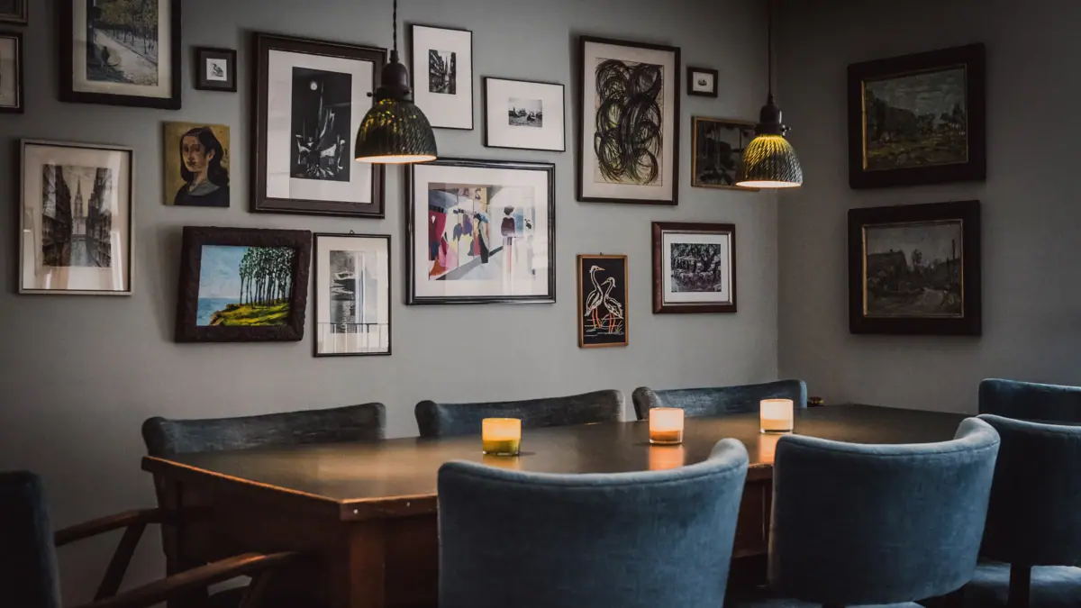 A table with candles and chairs in the office kitchen with pictures on the wall.
