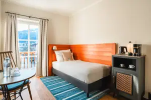 Single bed with patio door and small table.