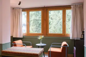 A seating area with two armchairs in front of a window in the Chambre hotel room at the HENRI Hotel Garmisch-Partenkirchen.