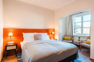 Bed with white cover and orange headboard