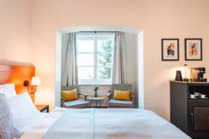 Bedroom with bed and chairs, including bedside table and pillows.
