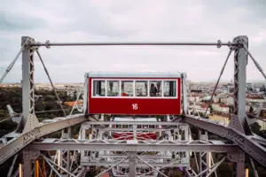Red and white ferris wheel against a cloudy sky.