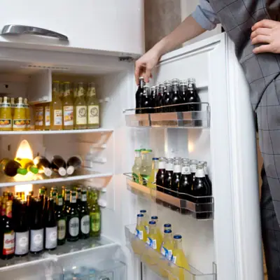 A man helps himself from a full fridge.