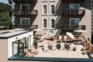 A group of people are sitting on a terrace with parasols and chairs.