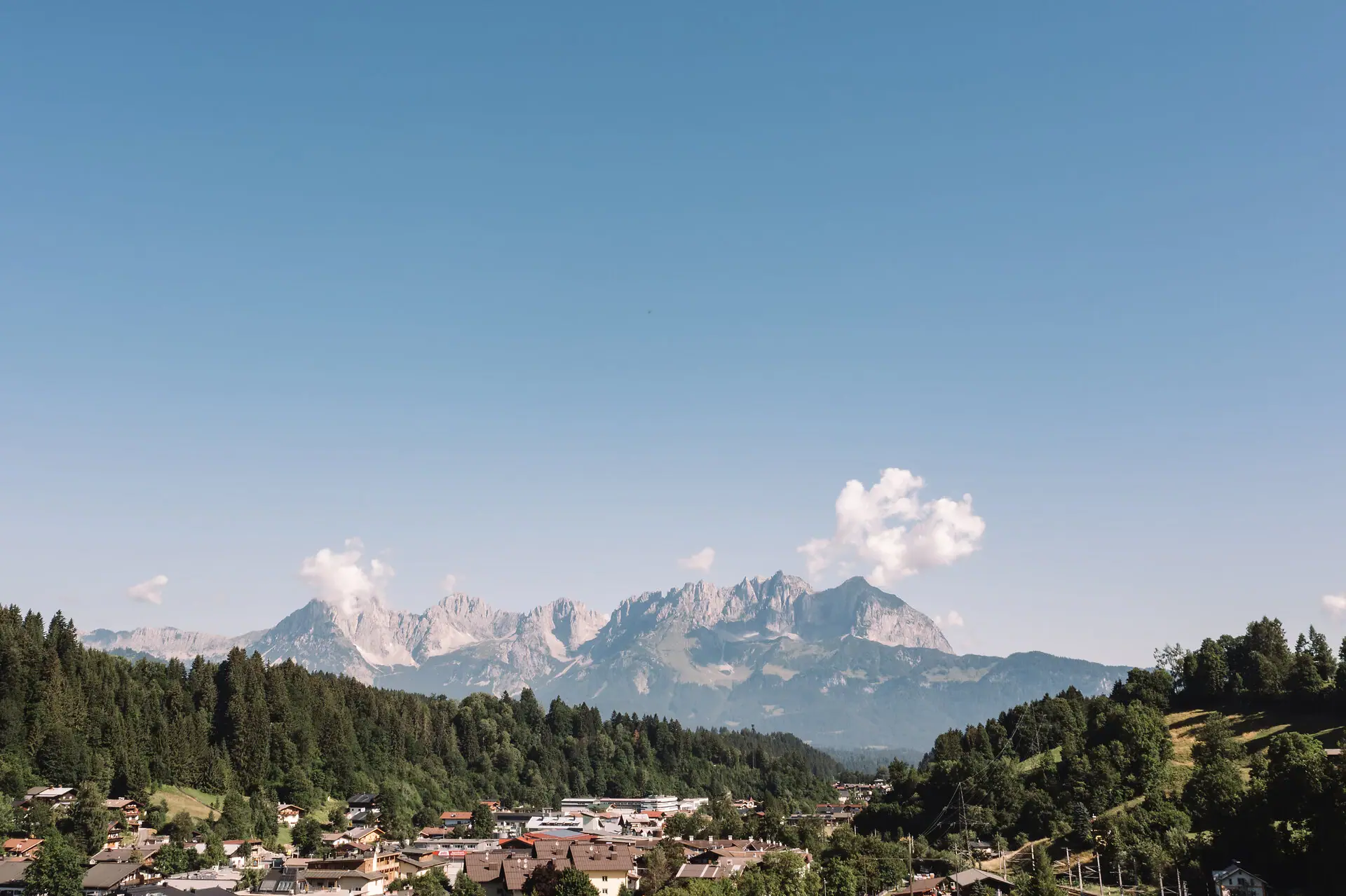 A town in the mountains with trees and a clear sky.
